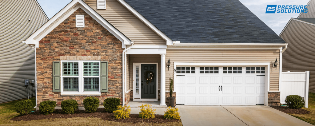 A clean exterior of a modern suburban house with stone veneer, tan siding, and a white garage door.